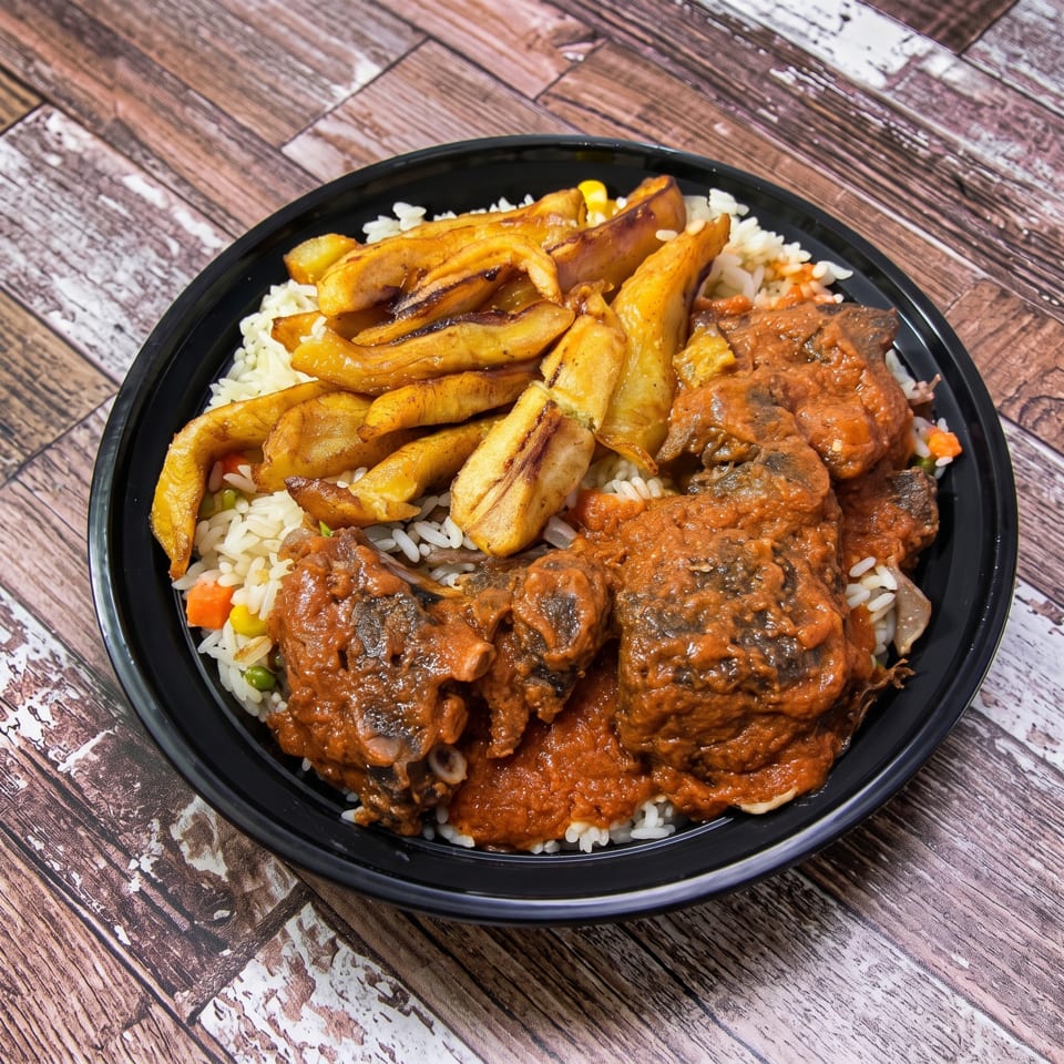 A black bowl filled with white rice, fried plantains, and meat in a rich red sauce.